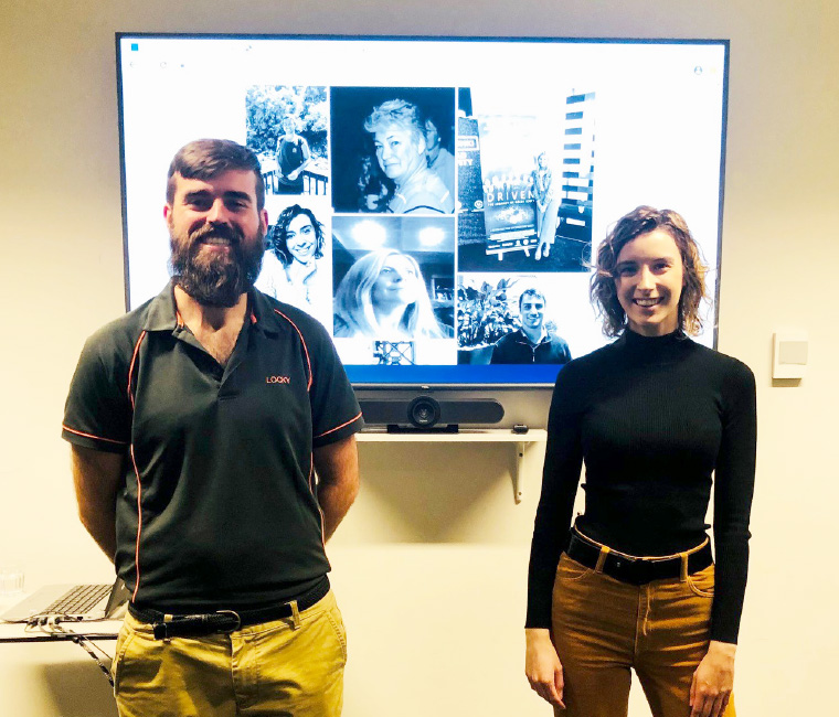 Locky Miller & Lauren Spear standing infrot of a large screen showing the launch of their new website