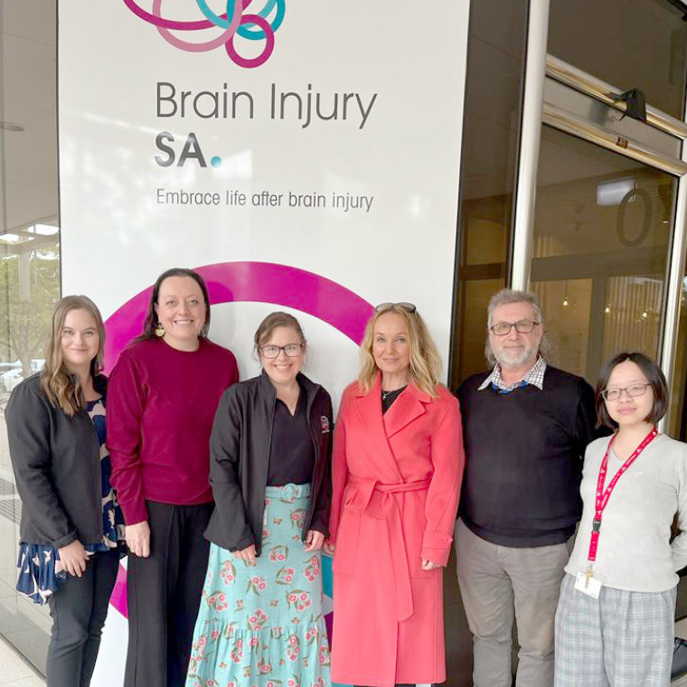 Staff standing in front of the window display banner featuring Brain Injury SA branding